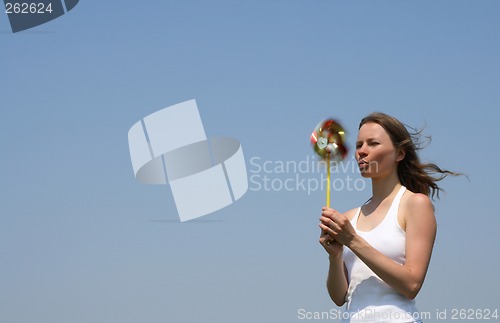 Image of Young woman blowing a colorful pinwheel