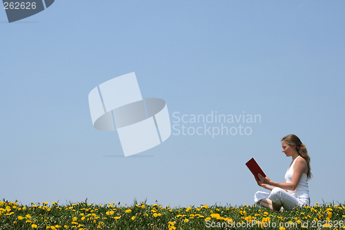 Image of Young woman reading a book outdoors