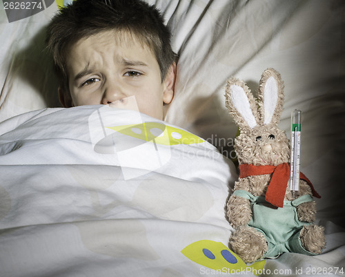 Image of Sick child in bed with teddy bear