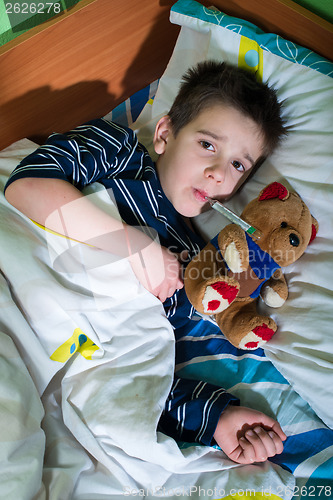 Image of Sick child in bed with teddy bear