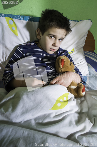 Image of Sick child in bed with teddy bear