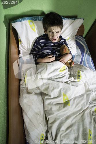 Image of Sick child in bed with teddy bear