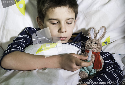 Image of Sick child in bed with teddy bear