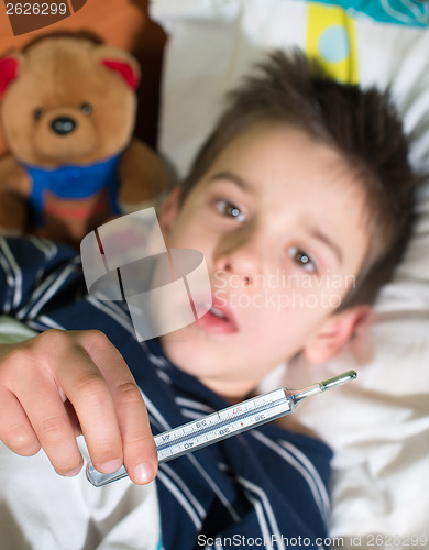 Image of Sick child in bed with teddy bear