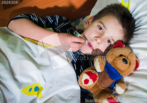 Image of Sick child in bed with teddy bear