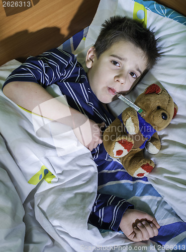 Image of Sick child in bed with teddy bear