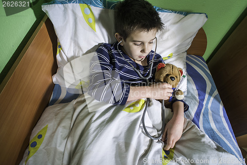 Image of Sick child in bed with teddy bear