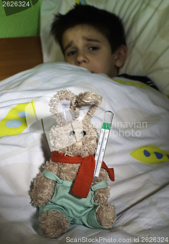 Image of Sick child in bed with teddy bear