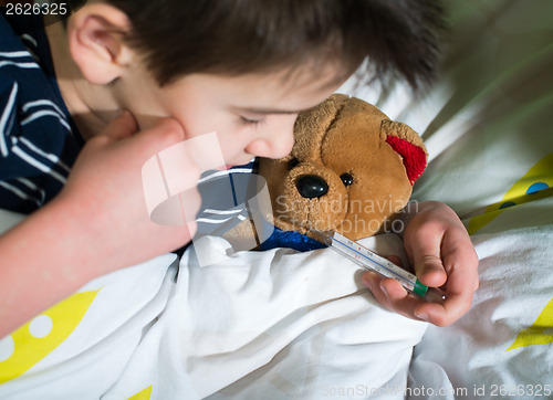 Image of Sick child in bed with teddy bear