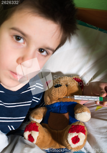 Image of Sick child in bed with teddy bear