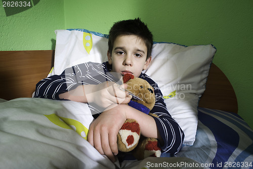 Image of Sick child in bed with teddy bear