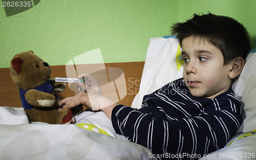 Image of Sick child in bed with teddy bear