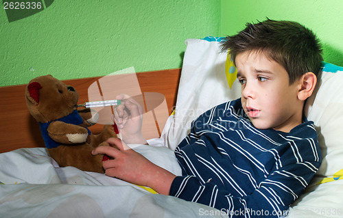 Image of Sick child in bed with teddy bear