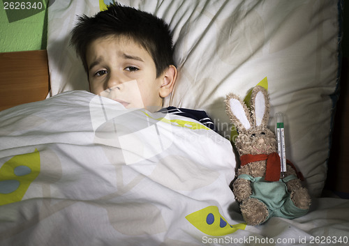 Image of Sick child in bed with teddy bear