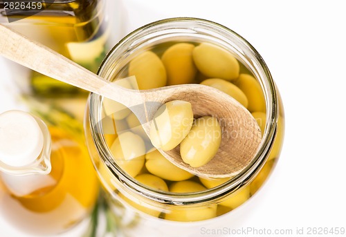 Image of Close up green olives preserved in bank, bottle of olive oil, rosemary