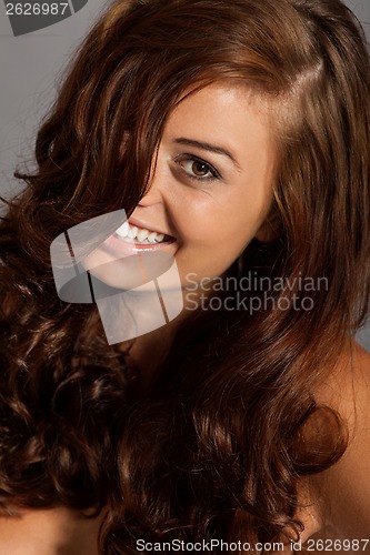 Image of young woman portrait with shiny healthy brown curly hair