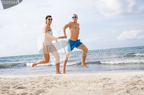 Image of young happy couple walking on beach sunset holiday