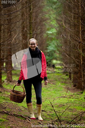 Image of young woman collecting mushrooms in forest