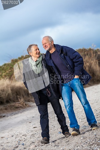 Image of happy elderly senior couple walking on beach