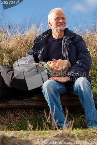 Image of happy senior couple relaxing together in the sunshine