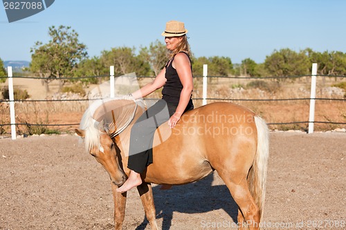 Image of young woman training horse outside in summer