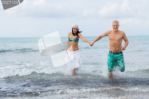 Image of young happy couple walking on beach sunset holiday