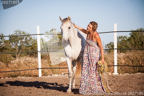 Image of young woman walking a road with horse