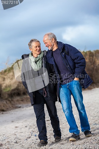 Image of happy elderly senior couple walking on beach