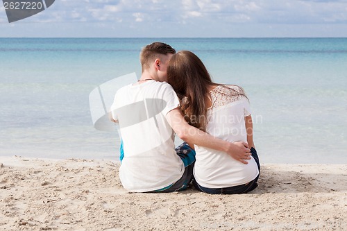 Image of romantic young couple sitting on the beach in summer