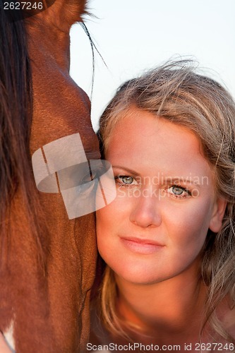 Image of young woman training horse outside in summer