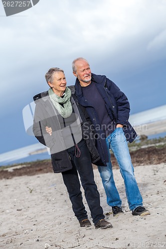 Image of happy elderly senior couple walking on beach