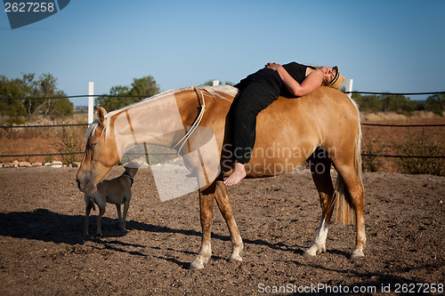 Image of young woman training horse outside in summer