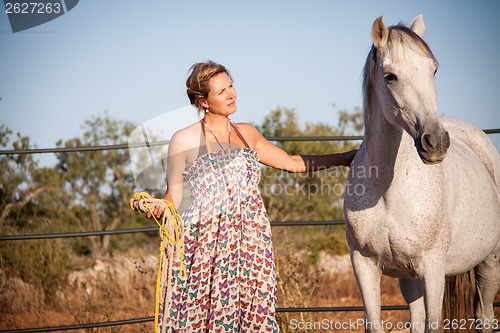 Image of young woman walking a road with horse