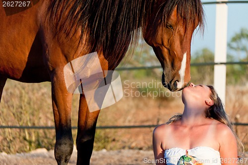 Image of young woman training horse outside in summer