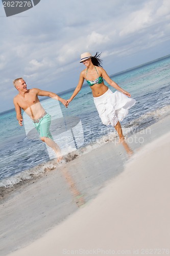 Image of young happy couple walking on beach sunset holiday