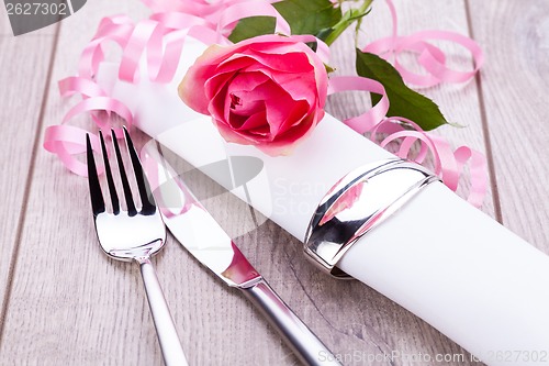 Image of Table setting with a single pink rose