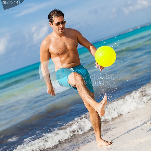 Image of happy young adult man playing beach ball in summer 