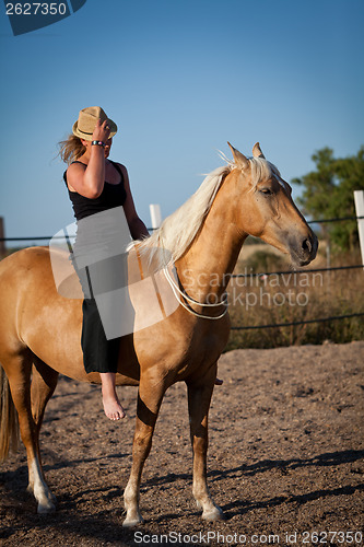 Image of young woman training horse outside in summer