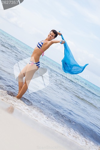 Image of Carefree woman on a beach with a floating scarf