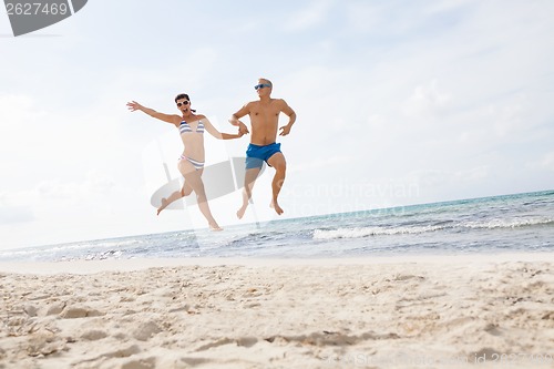 Image of young happy couple walking on beach sunset holiday