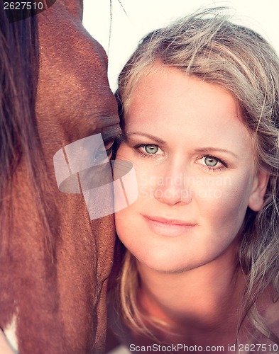 Image of young woman training horse outside in summer