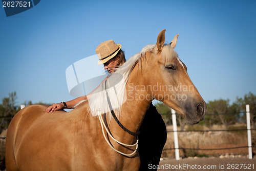 Image of young woman training horse outside in summer