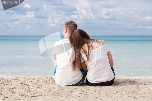 Image of romantic young couple sitting on the beach in summer