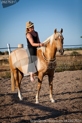 Image of young woman training horse outside in summer