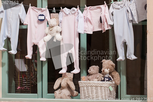 Image of baby clothing and teddy bear in window