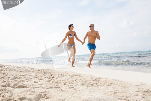 Image of young happy couple walking on beach sunset holiday