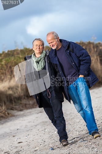 Image of happy elderly senior couple walking on beach