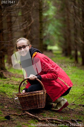 Image of young woman collecting mushrooms in forest