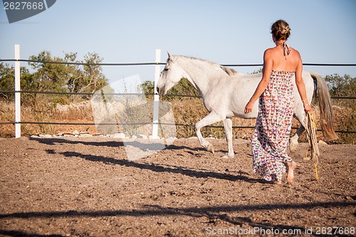 Image of young woman walking a road with horse