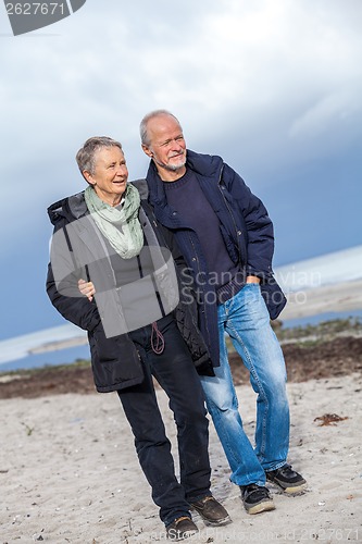 Image of happy elderly senior couple walking on beach